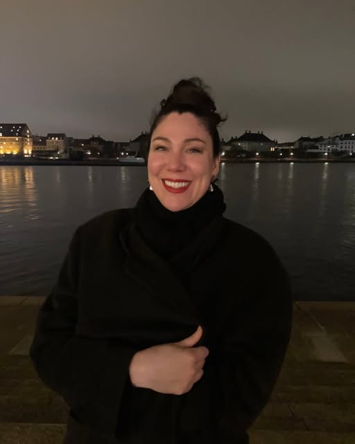 Christy smiling beside the waterfront at night